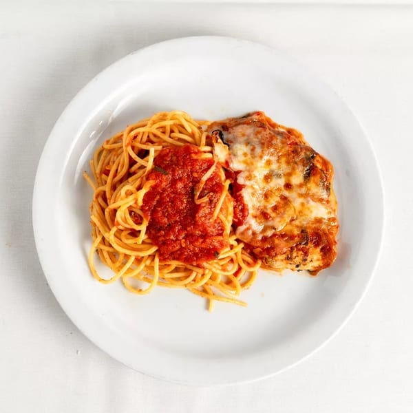 Chicken parmesan with melted cheese and spaghetti with red sauce on a white plate.