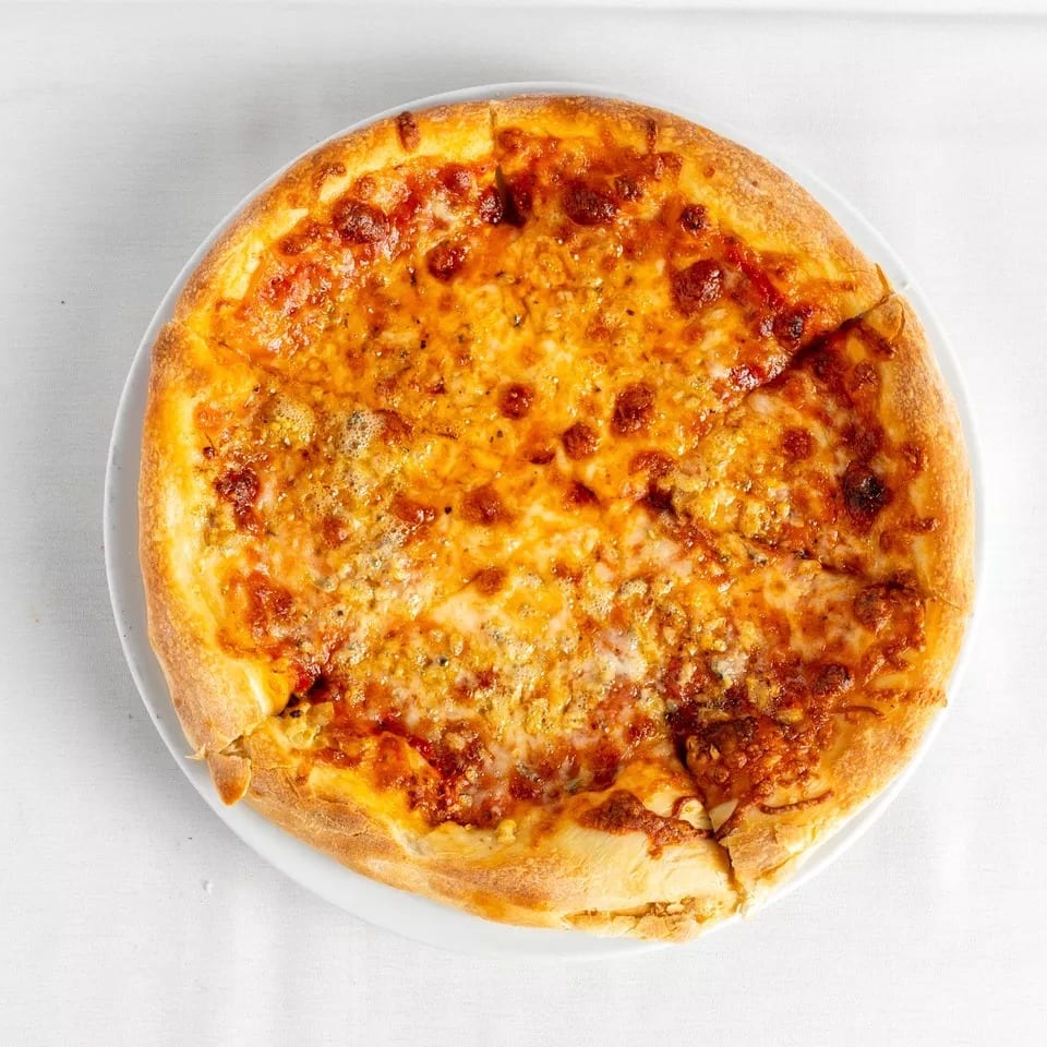A whole cheese pizza with a golden crust, cut into slices, on a white plate.