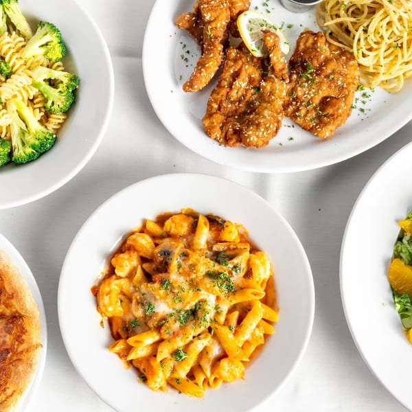 An overhead view of various Italian dishes, including pasta with broccoli, fried chicken, pizza, and salad.