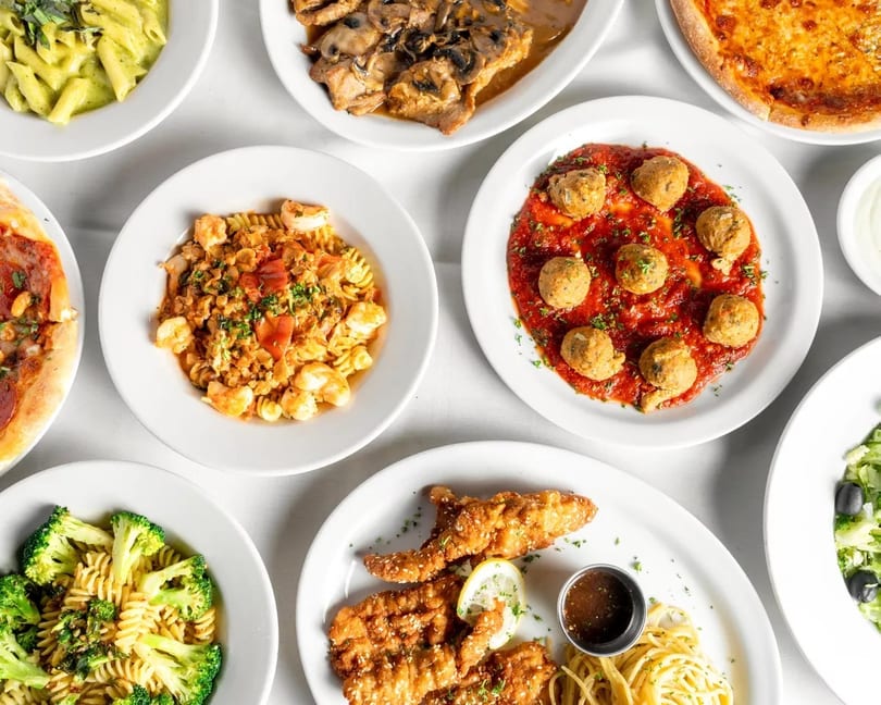An overhead view of various Italian dishes, including pasta, pizza, meatballs, and chicken cutlets.