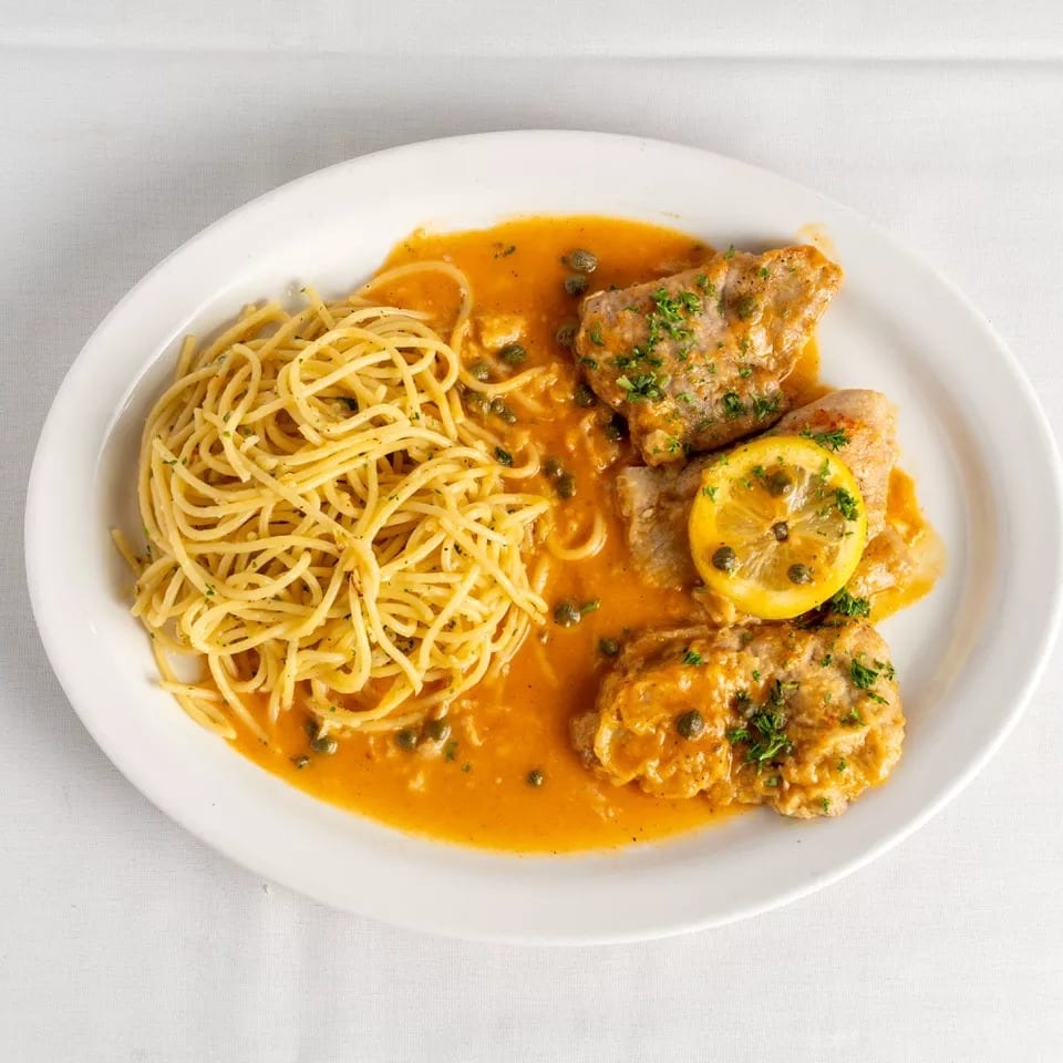 Chicken piccata with capers, lemon, and parsley, served with spaghetti in a rich orange sauce.