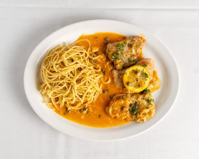 Chicken piccata with capers, lemon, and parsley, served with spaghetti in a rich orange sauce.